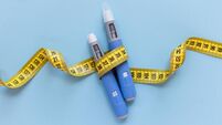 Two injectors dosing pens for subcutaneous injection of antidiabetic medication or anti-obesity medication hovering over a blue