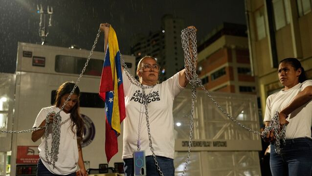 Relatives of people they consider to be detained for political reasons protest holding chains in front of a police station in Caracas (Ariana Cubillos/AP)