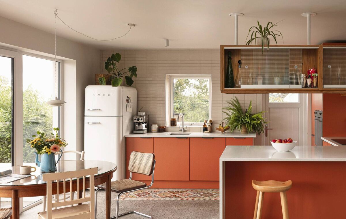 Cathy created a 1970s vibe in her kitchen with ceiling-mounted cabinets and her mid-century orange kitchen units give her joy. 