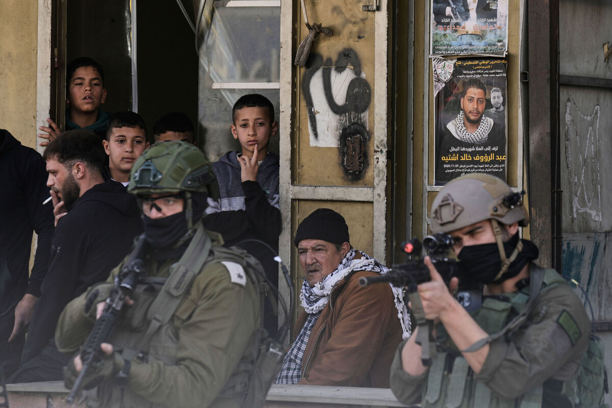 It's not just Gaza: Palestinian residents look on as Israeli soldiers aim their weapons in a market in Balata refugee camp in the West Bank on Sunday. Picture: Majdi Muhammad/AP