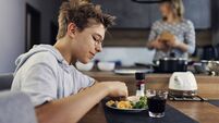 Teenage boy having scrambled eggs for breakfast