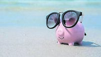 Pig piggy bank with sunglasses on the sand beach.