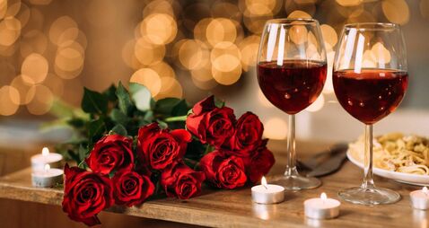 Roses, two glasses of red wine and candles on desk
