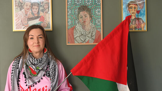 <p> Muireann Walsh, Behind her are two images by artist Anne-Marie Farrell and a painting from the Children of Gaza exhibition. Picture: Larry Cummins</p>