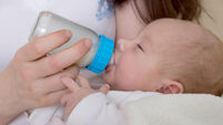 Newborn baby in the arms of his mother drinking from the feeding bottle
