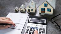 Businessman Calculating Tax By Small And Big House Models