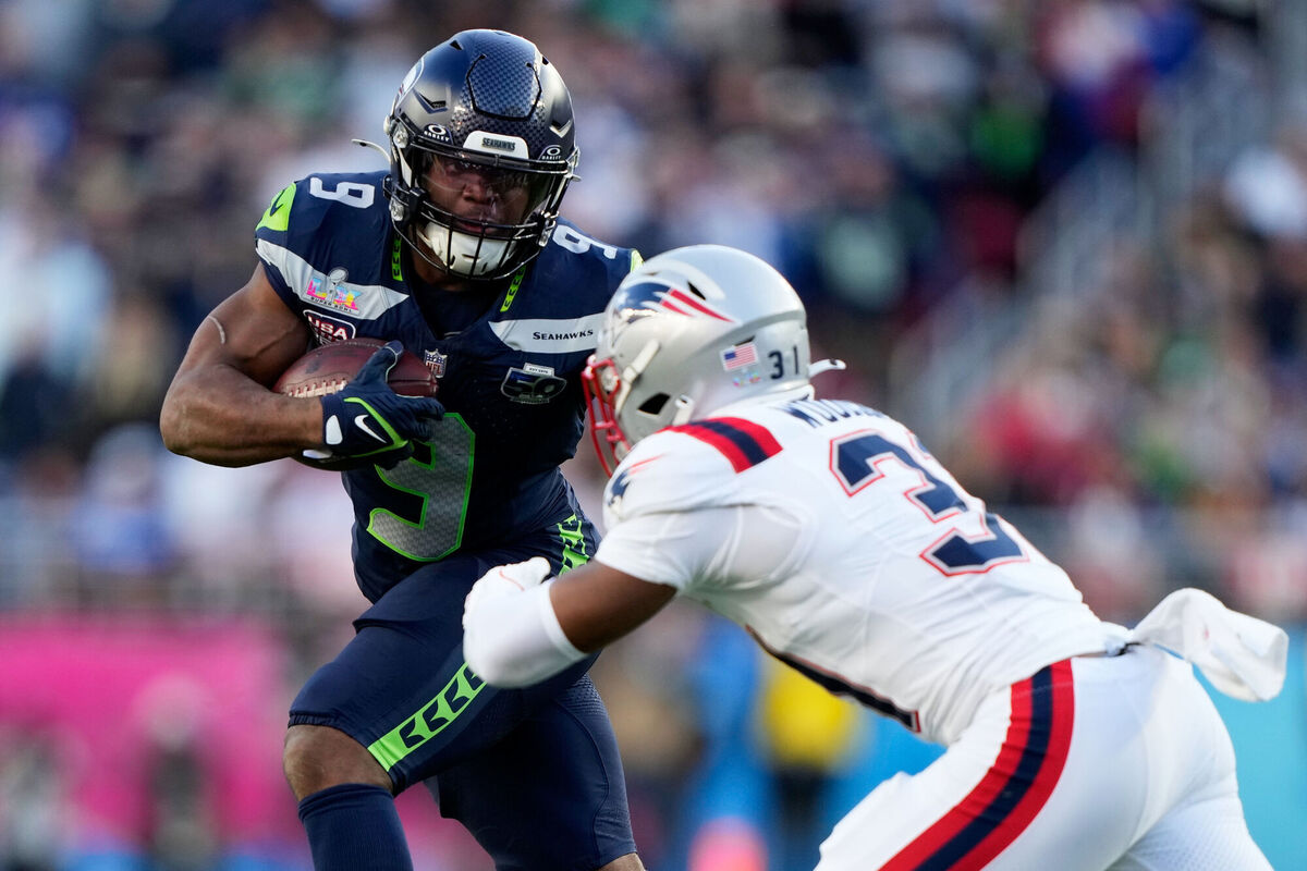 Seattle Seahawks running back Kenneth Walker III (9) runs against New England Patriots safety Craig Woodson during the first half of the NFL Super Bowl 60 football game, Sunday, Feb. 8, 2026, in Santa Clara, Calif. (AP Photo/Doug Benc)