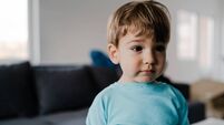 Portrait of a little boy in blue at home standing in the middle of the room
