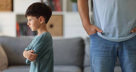 Annoyed father back to back with son ignoring each other after argue