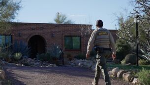 A member of the Pima County sheriffs office remains outside of Nancy Guthrie’s home (Ty O’Neil/AP)