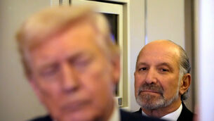 Commerce Secretary Howard Lutnick listens as President Donald Trump speaks to reporters on Air Force One (Mark Schiefelbein/AP)