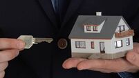 Businessman giving a key and holding small house in hand.
