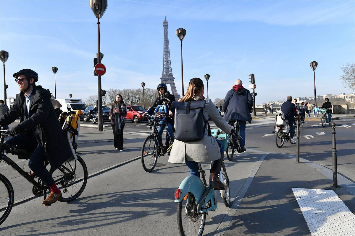 Cyclists heading to work use a cycle path with the Eiffel Tower in the background,.