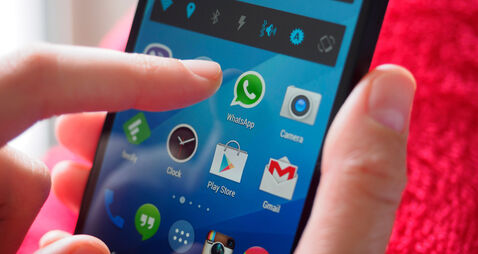 Person holding smartphone with WhatsApp messaging app