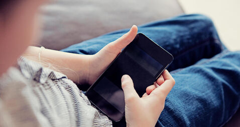 Over the shoulder view of a child using a smartphone in a home environment