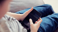 Over the shoulder view of a child using a smartphone in a home environment