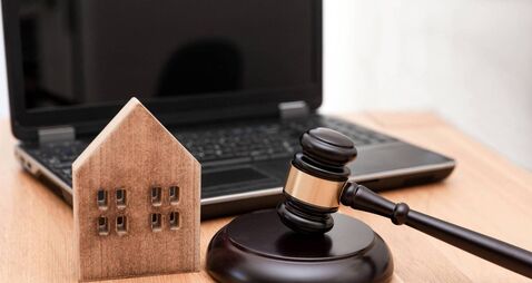 Wooden House Model and Judge Gavel on Desk with Laptop in the Background ,Real Estate Law or property law concept