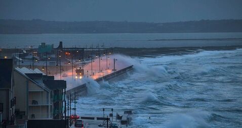 Giant waves and violent storm jumping over the pier in the seaside town of Tramore, Waterford, Ireland. horizontal format