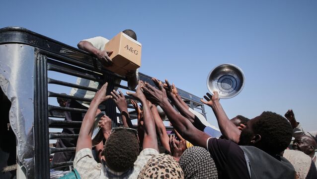 Sudanese families displaced from El-Fasher reach out as aid workers distribute food supplies (Marwan Ali/AP)