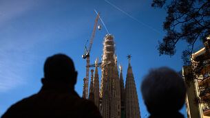 People watch as a crane lifts the upper arm of the cross on to the Tower of Jesus Christ (Emilio Morenatti/AP)