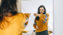 Self confident single woman pointing finger at her reflection in mirror, dancing and felling good