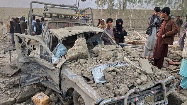 Local residents stand next to a damaged car at the site of a cross-border Pakistani army strike in the Behsud district of Nangarhar province, (Afghanistan Hedayat Shah/AP)