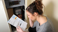 Young woman 20s attempting to read and understand her electricity meter reading and energy bill