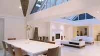 Dining table, sofas and skylights in open dining and living area of modern house