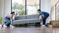 Couple carrying a couch while moving into their new home