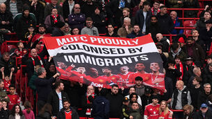 <p>Manchester United fans hold up a banner reading ‘MUFC proudly colonised by immigrants’ during the match against Crystal Palace at Old Trafford. Pic: Martin Rickett/PA</p>