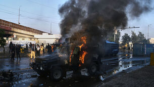 <p>Police officers walk past a burning police's armoured vehicle, which was set on fire by Shiite Muslims during a protest to condemn the killing of Iranian supreme leader Ayatollah Ali Khamenei, in Karachi, Pakistan, on Sunday. Picture: Ali Raza/AP</p>