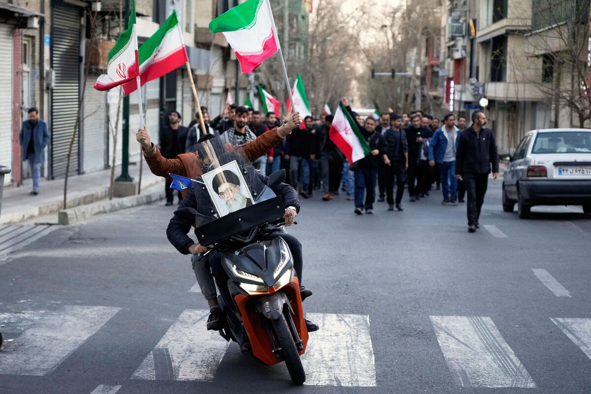 Two men on a motorcycle decorated with a picture of the late Iranian Supreme Leader Ayatollah Ali Khamenei ride ahead a group of government supporters near Khamenei's residency in Tehran. Picture: AP Photo/Vahid Salemi