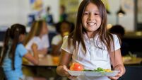 Happy elementary school girl with healthy food in cafeteria