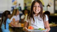 Happy elementary school girl with healthy food in cafeteria