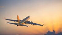 Passenger airplane flying above clouds during sunset