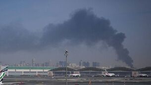 <p>A plume of smoke caused by an Iranian strike is seen in the background as Emirates planes are parked at Dubai International Airport after its closure in Dubai, United Arab Emirates, Sunday, March 1, 2026. Picture: AP Photo/Altaf Qadri</p>