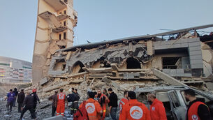 Rescue workers gather in front of the destroyed centre of a Lebanese Islamic group hit by an Israeli strike, in the southern port city of Sidon, Lebanon (Mohammed Zaatari/AP)