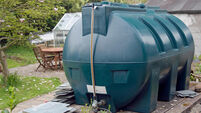 A large green plastic oil tank in a rural Cornish garden
