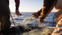 Fisherman at work pulling fishing net on trawler