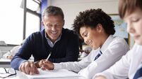 High School Tutor Giving Male Student Wearing Uniform One To One Tuition At Desk