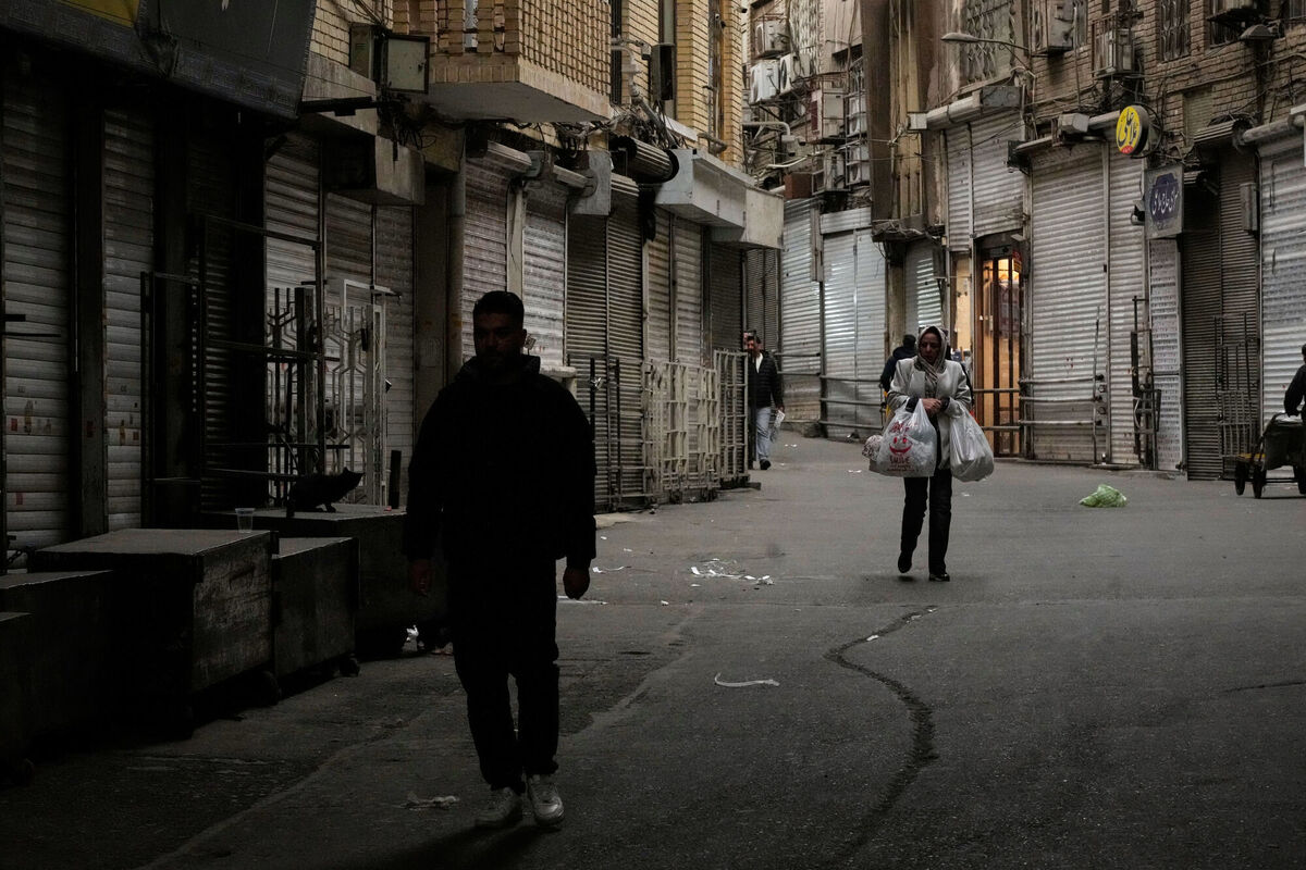 A woman carries her groceries as people walk along the mostly empty Tajrish traditional bazaar, where most shops are closed, in northern Tehran, Iran, on Tuesday. Picture: Vahid Salemi/AP