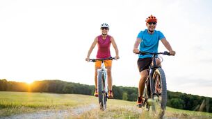 40-50 years old sporty couple cycling on electric mountain bikes in rural environment