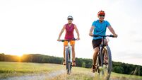 40-50 years old sporty couple cycling on electric mountain bikes in rural environment
